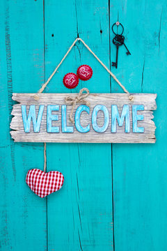 Welcome sign with heart, bottle caps and keys hanging on teal blue door