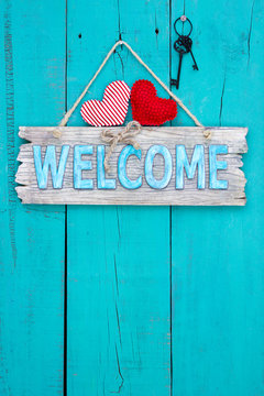 Welcome sign with hearts and keys hanging on teal blue door