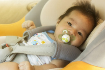 Baby child fastened with security belt in safety car seat