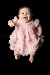 baby in a pink dress laughing