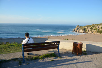 turista disfrutando de las vistas de la Playa de Usgo, Cantabria