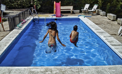Mujer y niño saltando a la piscina