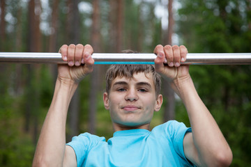 The teenager doing exercise on a horizontal bar