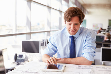 Male architect using tablet computer at a desk in an office
