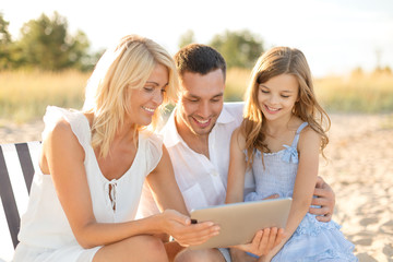 smiling family at beach with tablet pc computer
