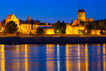Old town of Torun at night reflected in Vistula river, Poland