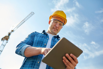 builder in hardhat with tablet pc at construction
