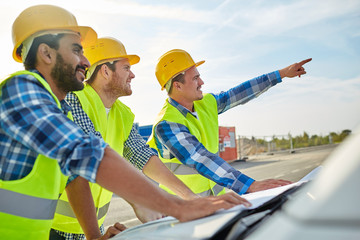 close up of builders with blueprint on car hood