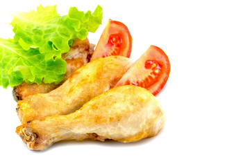 chicken legs on a white plate with slices of tomato and lettuce and  isolated on white background