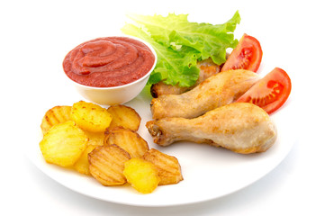 chicken legs dipped in ketchup on a white plate with lettuce and roasted potatoes  isolated on white background
