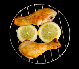 chicken legs on the grill with sliced lemon view from above isolated on black background