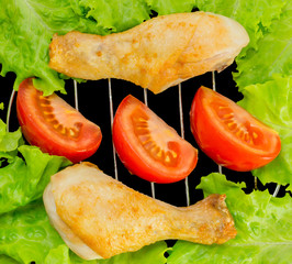 chicken legs on the grill with tomato slices and lettuce