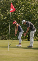 Nice couple playing golf in a sunny day on a nice course