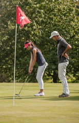 Nice couple playing golf in a sunny day on a nice course