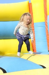 A young girl playing on a bouncy castle during the summertime