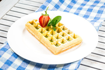 Plate of belgian waffles with ice cream, caramel sauce and fresh fruit