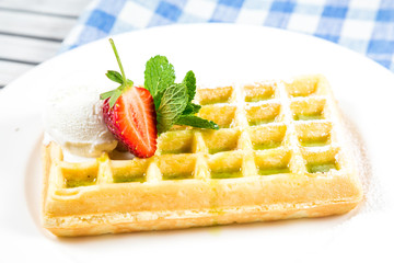 Plate of belgian waffles with ice cream, caramel sauce and fresh fruit