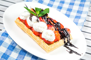 Belgium waffles with chocolate sauce, ice cream and strawberries
