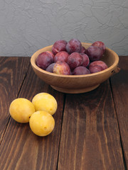 Plums in a plate on old wooden table