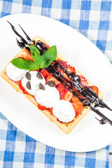 Belgium waffles with chocolate sauce, ice cream and strawberries
