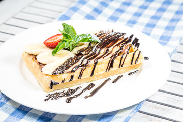 Plate of belgian waffles with ice cream, caramel sauce and fresh fruit