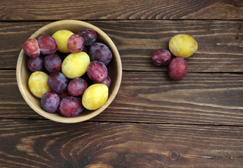 Plums in a plate on old wooden table