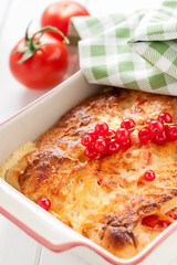 Bread pudding with cheese and tomatoes in ceramic plate with green napkin