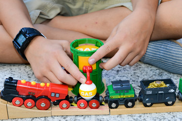 Boy playing with a wooden train set on a garden