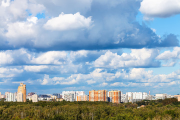 Fototapeta na wymiar low blue clouds over green forest and city