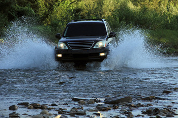 Obraz na płótnie Canvas Car SUV overcomes a mountain stream at high speed with splashes