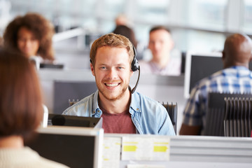 Young man working in a call centre, looking to camera