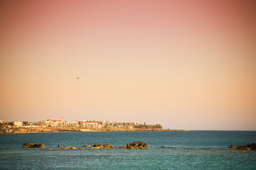 Naklejka premium Rocky shore of the Mediterranean Sea. Town on the horizon. Toned