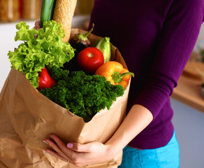 Assorted fruits and vegetables in brown grocery bag holding a