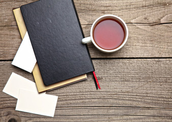 laptop, tea, business card with pen on old wooden desk