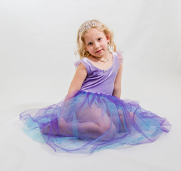 Portrait of a blonde girl in a purple dress and tiara