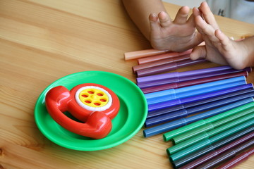 Close up of colored pens arranged on the table with the child's hands and toys