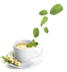 Mint leaves falling in cup of herbal tea, isolated on white