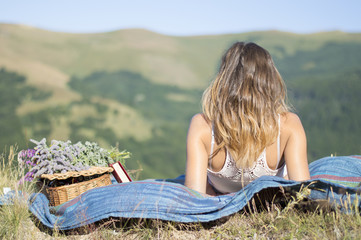 Young woman laying on a blanket on a picnic in the field