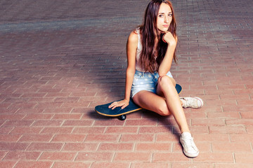 Fototapeta na wymiar Redhair women is sitting on skateboard outdoors 