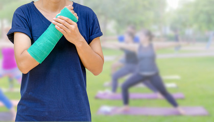 broken arm with green cast on blurred woman fitness group - yoga