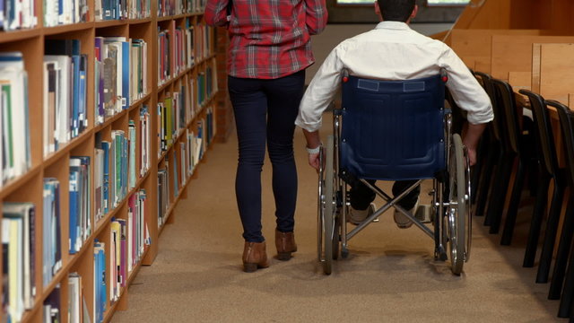 Disabled student and friend in the library