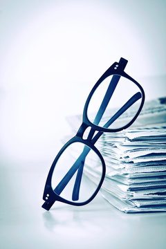 reading eyeglasses with stacking of newspaper background 