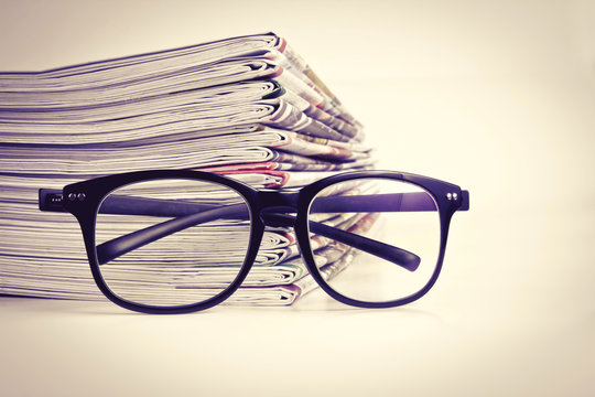 selective focus on reading eyeglasses with stacking of newspaper
