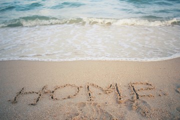 The word home written in sand on beach