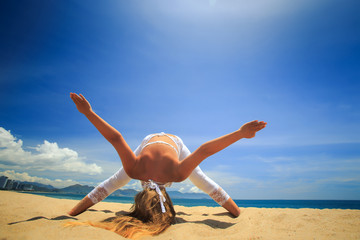 girl in lace in yoga asana downward facing head balance on beach