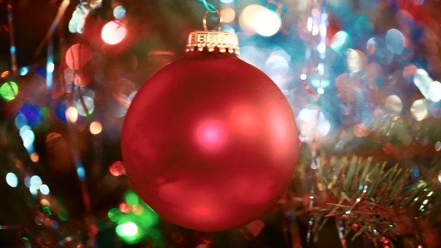 Illuminated Christmas tree with bright red sphere ornament (bauble). Sliding shot.