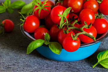 Fresh cherry tomatoes in a metal bowl on a dark background