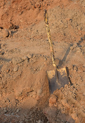 Old yellow shovel in the ploughed ground with sunlight effect