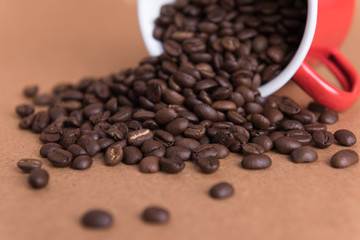 Roast coffee beans and vintage red cup on wood background