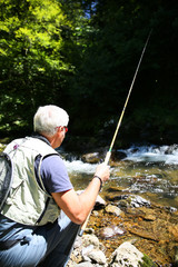 Fly-fisherman fishing in river on summer season
